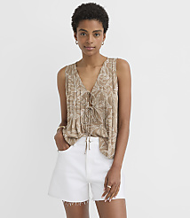 A woman in a tan, leaf-patterned top and white shorts stands against a plain white background. carousel Product Image 1