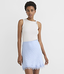 A woman in a light gray sleeveless top and a light blue textured skirt with lace trim stands against a plain white background. carousel Product Image 1