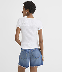 A woman in a white textured top and denim shorts stands against a plain white background. carousel Product Image 2