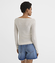 A woman in a light-colored off-the-shoulder sweater and denim shorts stands against a plain white background. carousel Product Image 2