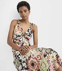 A woman in a patterned dress sits against a plain white background. carousel Product Image 2