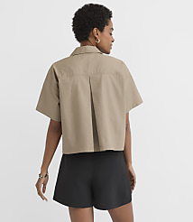 A woman in a tan cropped shirt and black shorts stands against a plain white background. carousel Product Image 3