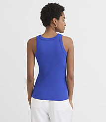 A woman in a blue ribbed tank top and white pants stands against a plain white background. carousel Product Image 3