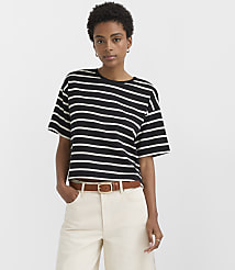 A woman in a black and white striped t-shirt and cream pants stands against a plain white background. carousel Product Image 1