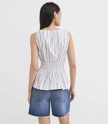 A woman in a striped peplum top and denim shorts stands against a plain white background. carousel Product Image 2