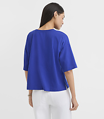 A woman in a blue t-shirt and white pants stands against a plain white background. carousel Product Image 3