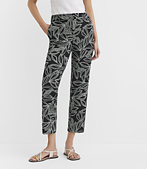 A person models black pants with a white leaf pattern, standing against a plain white background. carousel Product Image 2
