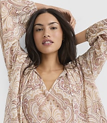 A woman with her arms behind her head wears a flowing, paisley-patterned blouse against a plain white background. carousel Product Image 2
