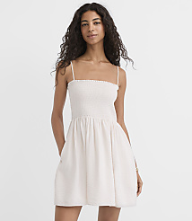 A woman in a white smocked dress stands against a plain white background. carousel Product Image 1
