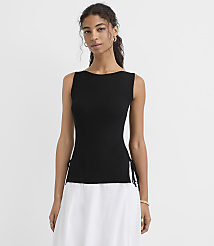 A woman in a black sleeveless top with white skirt stands against a plain white background. carousel Product Image 1