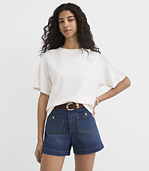A woman in a white t-shirt and denim shorts stands against a plain white background. carousel Product Image 1