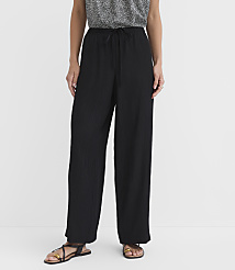A person stands in black wide-leg pants and sandals against a plain white background. carousel Product Image 2