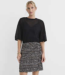 A woman in a black sheer top and a patterned skirt stands against a plain white background. carousel Product Image 1