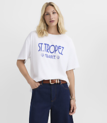 A woman in a white t-shirt with "ST. TROPEZ FRANCE" printed on it stands against a plain white background. carousel Product Image 1