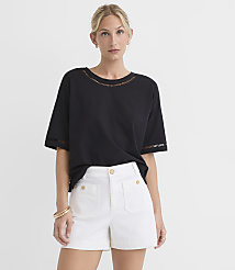 A woman in a black top and white shorts stands against a plain white background. carousel Product Image 1