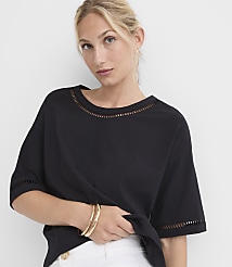 A woman in a black top with cut-out details on the neckline and sleeves poses against a plain white background. carousel Product Image 2