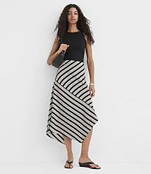 A woman in a black top and a striped asymmetrical skirt stands against a plain white background, carrying a black purse. carousel Product Image 1
