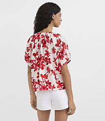 A woman in a white floral top and white shorts stands against a plain white background. carousel Product Image 3