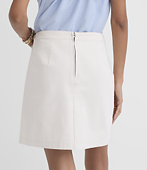 A person wearing a light blue top and a cream-colored a-line skirt with a zipper closure stands against a plain white background. carousel Product Image 3