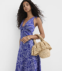 A woman in a blue floral dress holds a crocheted bag in front of a white background. carousel Product Image 3