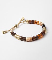 A beaded bracelet with earthy tones rests on a plain white background. carousel Product Image 1