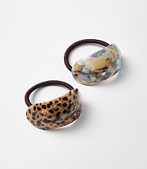 Two decorative hair ties, one with a leopard print design and the other with a marbled pattern, rest on a plain white background. carousel Product Image 1
