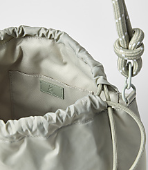 A light green drawstring bag with a white-speckled rope strap is shown against a plain white background. carousel Product Image 2