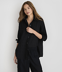 A woman in a black textured shirt and black pants stands against a plain white background. carousel Product Image 1