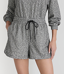 A person models a grey and white patterned romper with a black drawstring in the foreground, against a plain white background. carousel Product Image 2