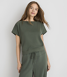 A young woman in a green top and pants stands against a plain gray background. carousel Product Image 1