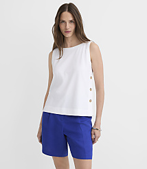 A woman in a white sleeveless top and blue shorts stands against a plain white background. carousel Product Image 1