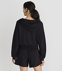 A woman in a black hoodie and shorts stands against a plain white background. carousel Product Image 3