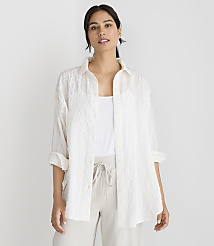 A woman in a white textured shirt and light-colored pants stands against a plain white background. carousel Product Image 1