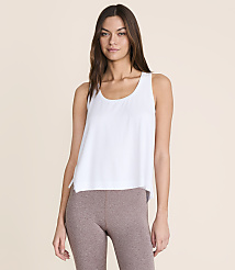 A woman in a white tank top and brown leggings stands against a plain, light peach background. carousel Product Image 1