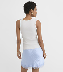 A woman in a white tank top and a light blue slip skirt stands against a plain white background. carousel Product Image 2