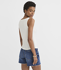 A woman in a white sleeveless top and denim shorts stands against a plain, light background. carousel Product Image 3
