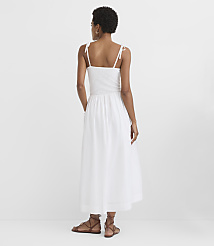 A woman in a white smocked sundress stands with her back to the viewer against a plain white background. carousel Product Image 2