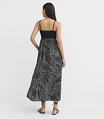 A woman in a black and white patterned maxi dress stands with her back to the camera against a plain white background. carousel Product Image 2
