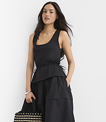 A woman in a black dress stands against a plain white background, holding a patterned bag. carousel Product Image 3
