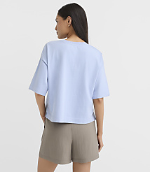 A woman in a light blue t-shirt and olive shorts stands against a plain white background. carousel Product Image 3