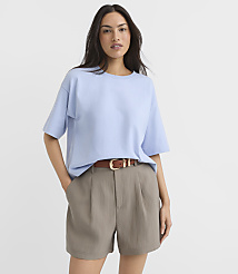 A woman in a light blue t-shirt and taupe shorts stands against a plain white background. carousel Product Image 1