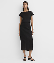 A woman in a black ribbed dress stands against a plain white background. carousel Product Image 1