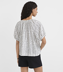 A woman in a patterned blouse and black shorts stands against a plain white background. carousel Product Image 3