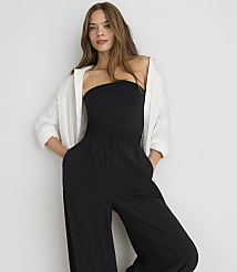 A woman in a black strapless jumpsuit and white open shirt stands against a plain white background. carousel Product Image 2