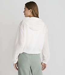 A woman in a white hooded jacket and green pants stands against a plain white background. carousel Product Image 3