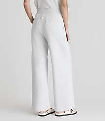 A person wearing light gray wide-leg sweatpants and white sandals stands against a plain white background. carousel Product Image 3