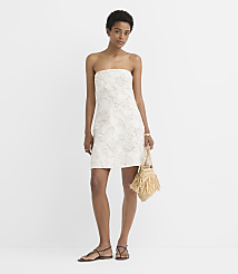 A woman in a strapless floral dress and sandals stands with a fringed straw bag against a plain white background. carousel Product Image 4