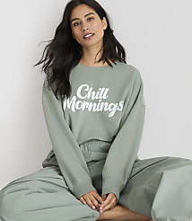 A woman in a green sweatshirt and pants sits against a plain white background. carousel Product Image 2