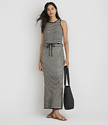 A woman in a striped maxi dress and sandals stands against a plain white background, holding a black quilted tote bag. carousel Product Image 1