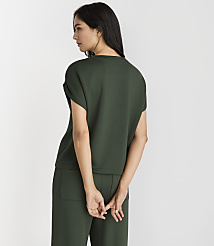 A woman in a dark green top and pants stands with her back to the viewer against a plain white background. carousel Product Image 3